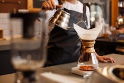 Professional barista preparing coffee using chemex pour over coffee maker and drip kettle. Alternati...