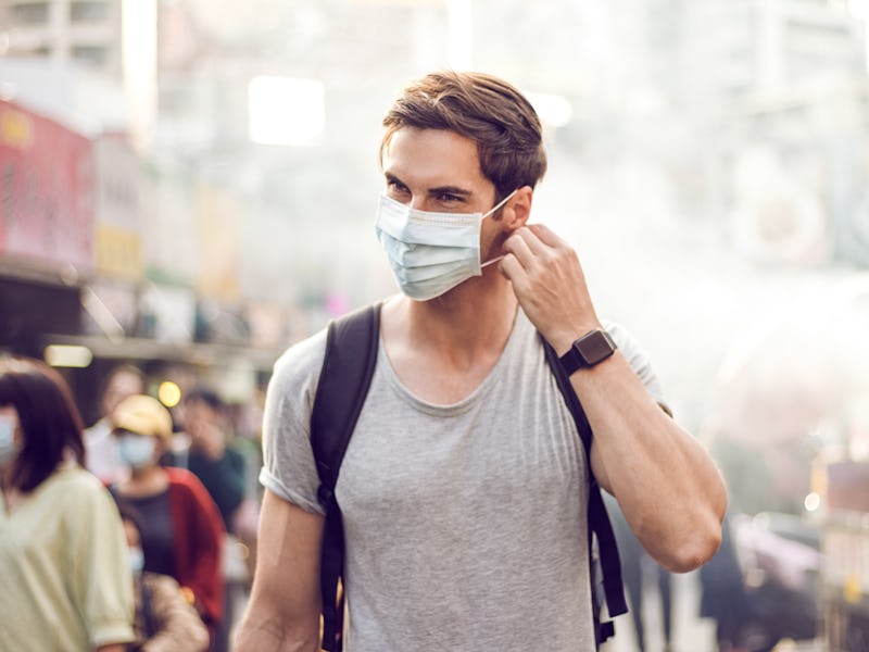 Young handsome man walking around night market in Taipei with backpack and wearing a face pollution ...