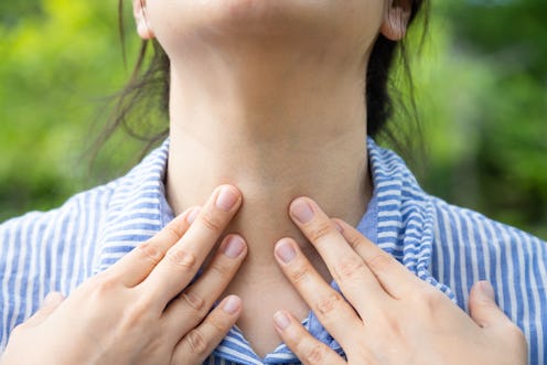 A woman touches at her sore tonsils. Here's how to make tonsil stones fall out at home.
