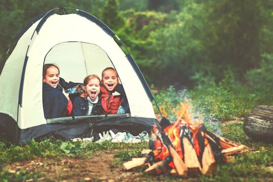 Children's tourism. Happy kids girls in campaign in a tent near fire