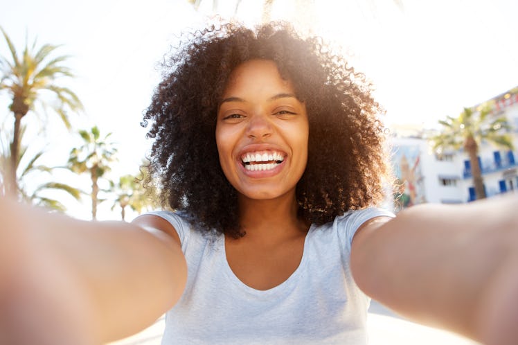 Selfie portrait of laughing black woman outside with curly hair