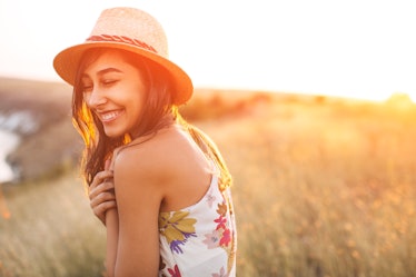 Lovely girl in stylish hat and summer dress smiling with closed eyes. Laughing young woman with sun ...