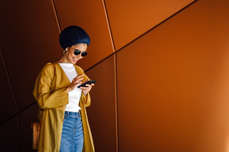 Portrait of a young and attractive Malay Muslim woman using her smartphone. She is tall, elegant and...