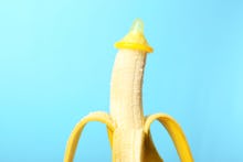 Condom on banana against color background. Safe sex concept