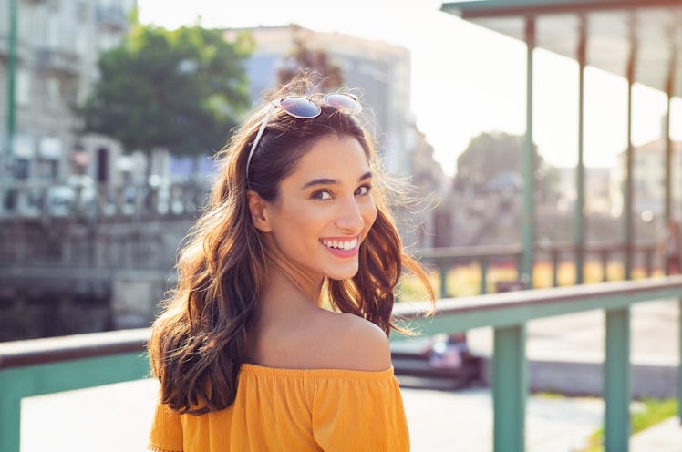 Happy latin woman looking behind while walking on street. Beautiful young woman enjoying vacation du...