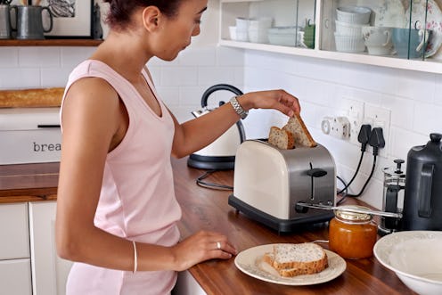 young woman making breakfast toast bread with toaster at home kitchen