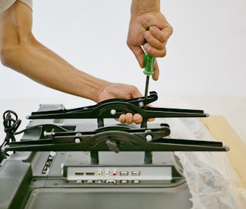 A technician is installing a wall mount on a television getting it ready to be put on a wall