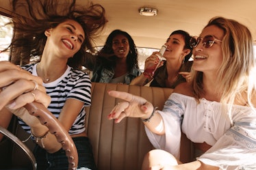 Group of happy young women laughing and enjoying in car during a road trip to vacation. Girls having...