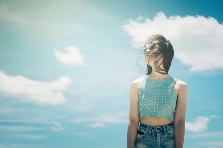 Portrait of a cute asian teenager young woman stand against blue sky and cloud background. wearing s...