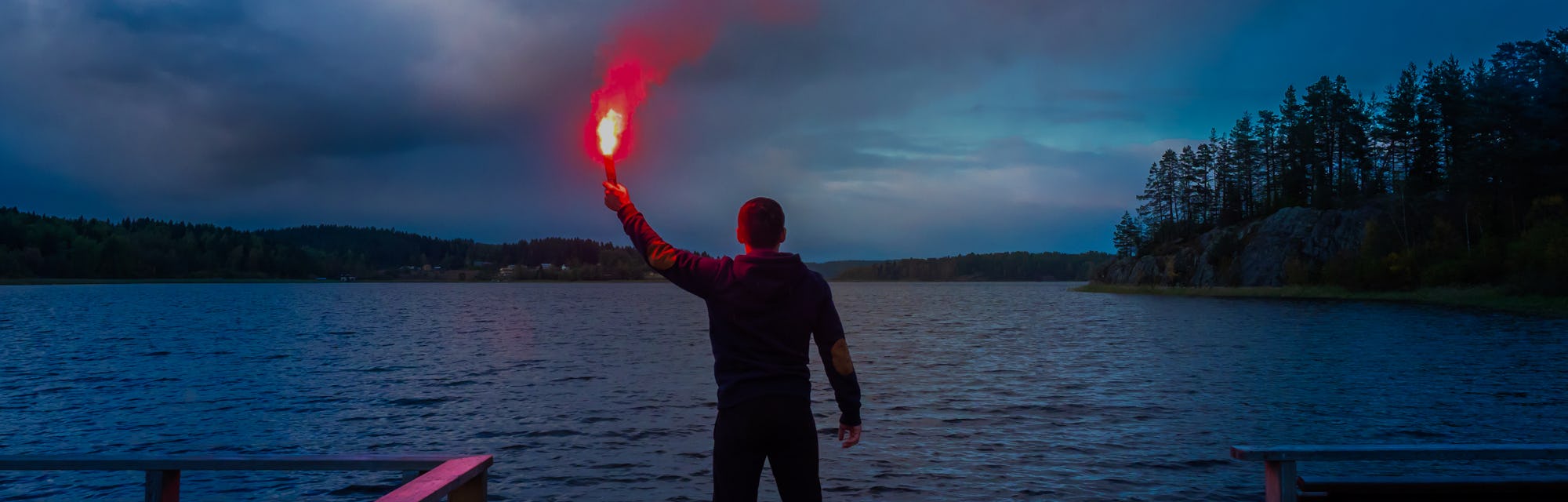 Signal for help. A man signals a torch in his hand. SOS. A man holds a torch in his hand.