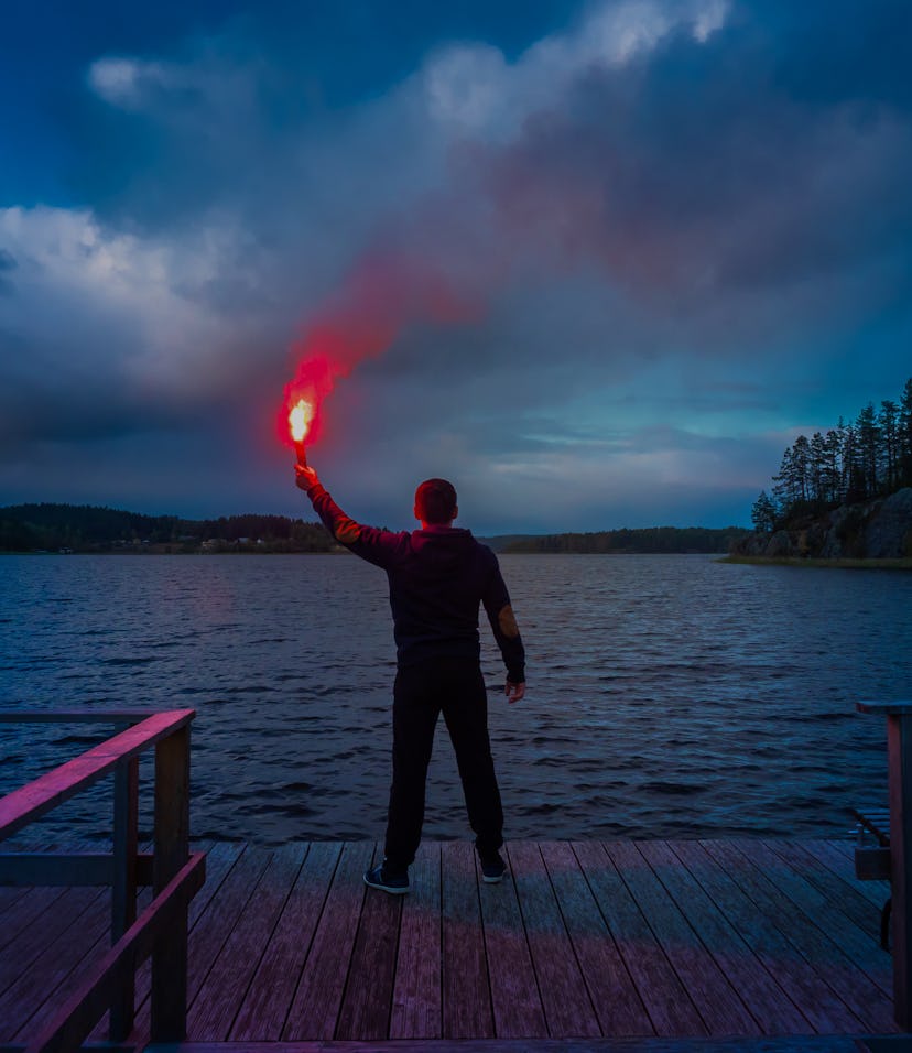 Signal for help. A man signals a torch in his hand. SOS. A man holds a torch in his hand.