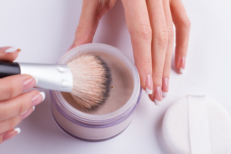 Beautiful french manicure. Women's hands holding the powder and brush.