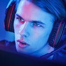 Portrait of the Young Handsome Pro Gamer Playing in Online Video Game, talks with Team Players throu...