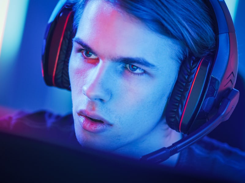 Portrait of the Young Handsome Pro Gamer Playing in Online Video Game, talks with Team Players throu...