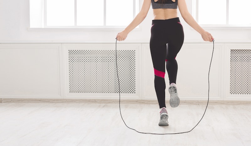 Unrecognizable woman jumping over the skipping rope in studio, crop, panorama, free space