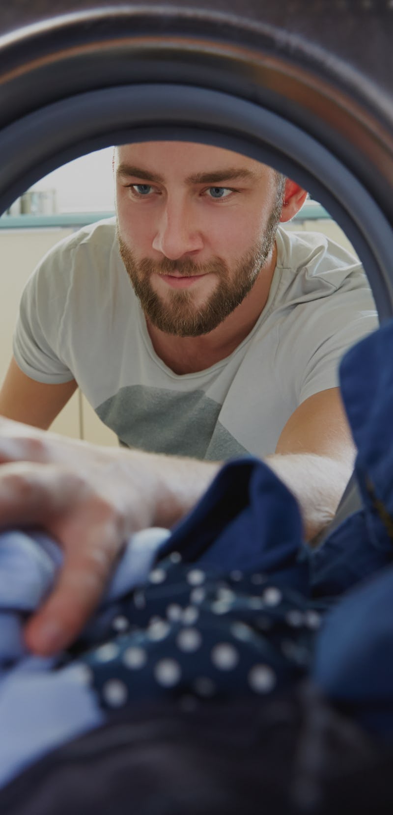 Man Doing Laundry Reaching Inside Washing Machine