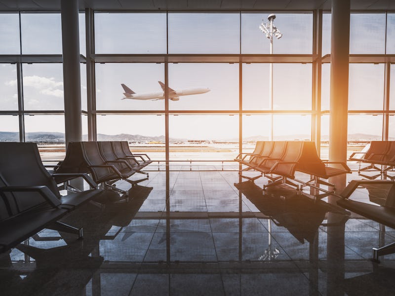 Wide-angle view of a modern aircraft gaining the altitude outside the glass window facade of a conte...