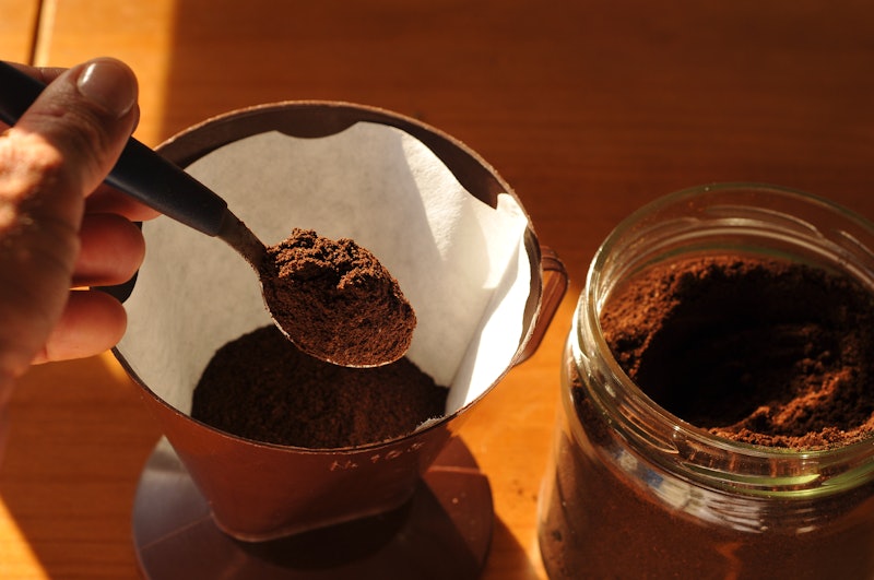 Preparing coffee, coffee strainer with coffee and spoon.