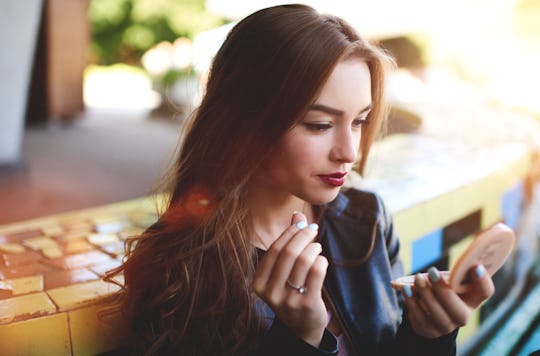 Attractive sexy woman making make-up woman applying lipstick outdoors. Charming hipster girl rouge l...