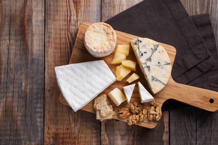 Tasting cheese dish on a wooden plate. Food for wine and romantic, cheese delicatessen on a wooden r...