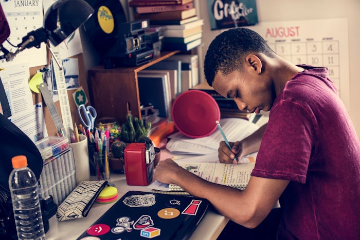 Teenage boy in a bedroom doing work stressed out and frustrated