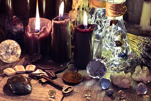 Magic crystals, ritual objects, runes, black candles and bottles on witch table. Occult, esoteric an...