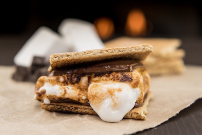 A roasted marshmallows melts in an assembled s'more that sits on the table. 