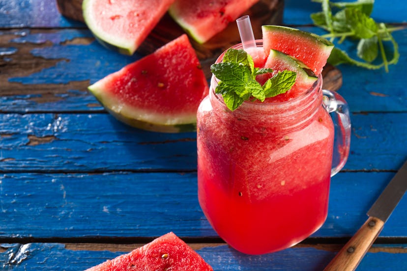 Tasty fresh appetizing watermelon drink smoothie with mint on blue table. Closeup. 