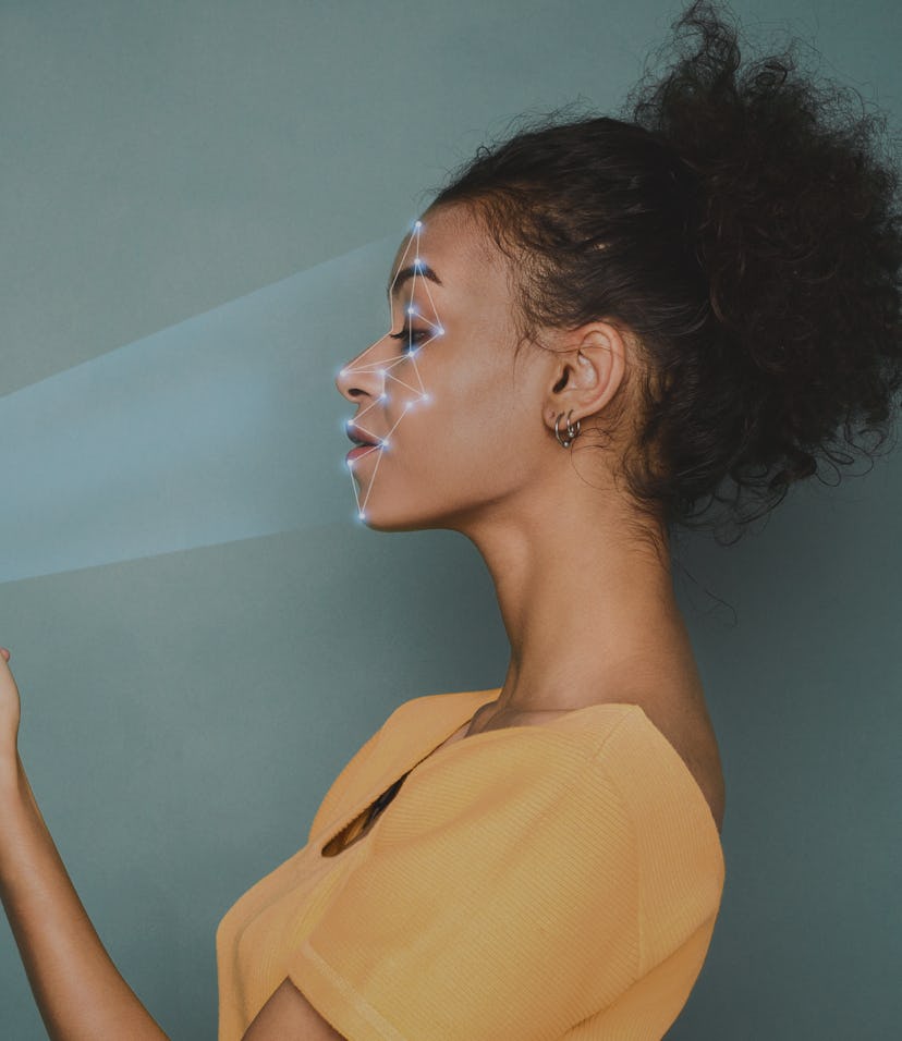 Woman scanning face with facial recognition system on smartphone, with rays coming out of the phone ...