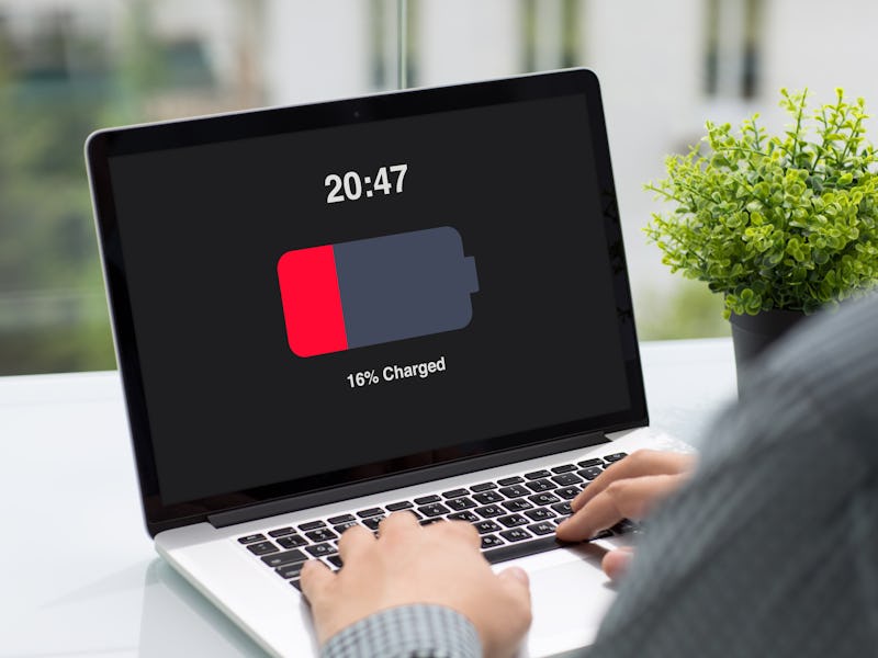 Man holding computer with low charged battery screen on table in cafe
