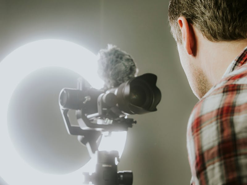 A man streaming, video recording with a mirror less camer and ring light.