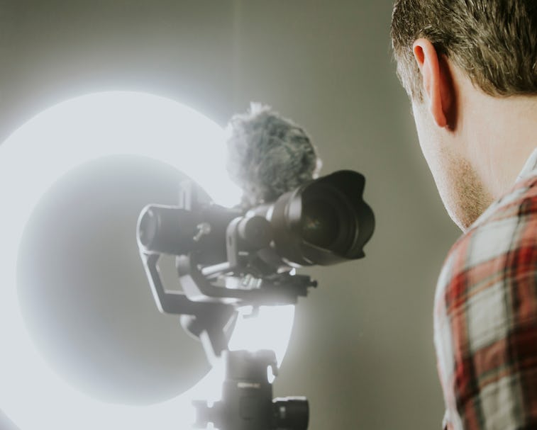 A man streaming, video recording with a mirror less camer and ring light.