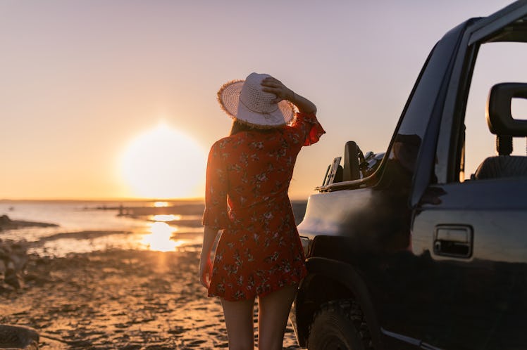 girl with happy hat at sunset on the beach with her convertible car