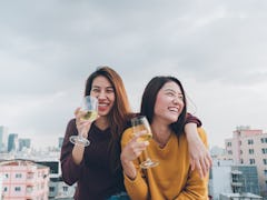 Two women are cuddled next to each other drinking wine and laughing on a rooftop. In numerology, lif...