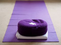 Purple coloured yoga mat and yoga cushion in a yoga room.