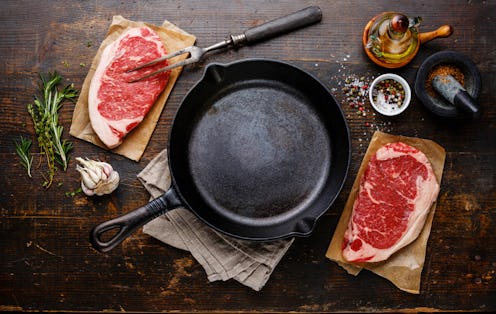 Raw fresh meat Steak Striploin for two with condiments around iron frying pan