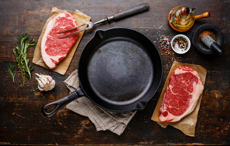 Raw fresh meat Steak Striploin for two with condiments around iron frying pan