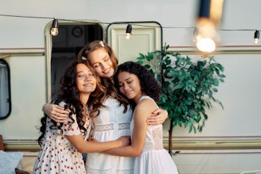 Beautiful multi ethnic girls hugging near camper van outdoors. Caucasian, african american and asian...