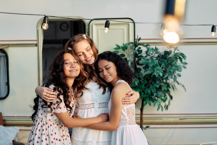 Beautiful multi ethnic girls hugging near camper van outdoors. Caucasian, african american and asian...