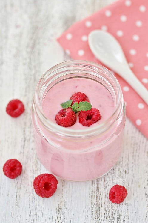 Homemade yoghurt with fresh raspberries and raspberry berries in a jar. light background. Soft focus...