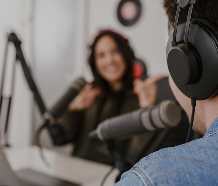 Man and woman in white shirts podcasters interview each other for radio podcast