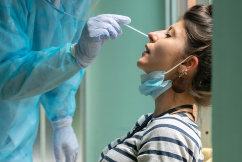 Healthcare worker with protective equipment performs coronavirus swab on Caucasian girl.Nose swab fo...