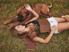 Calm and peace. Lying on the ground. Woman have a walk with her dog outdoors in the park. Having goo...