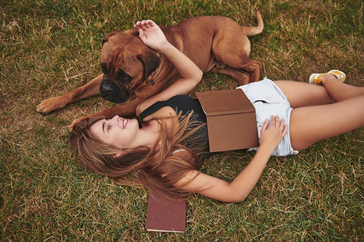 Calm and peace. Lying on the ground. Woman have a walk with her dog outdoors in the park. Having goo...