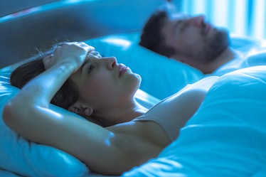 The woman with a headache lay near the man in the bed. night time