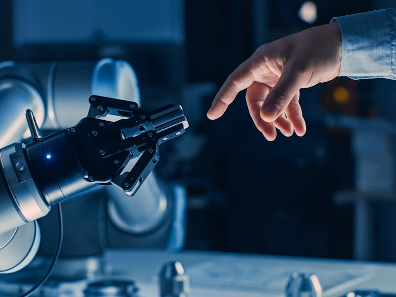 Futuristic Robot Arm Touches Human Hand in Humanity and Artificial Intelligence Unifying Gesture. Co...