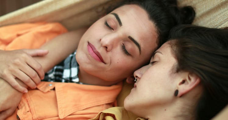 
Beautiful diverse lesbian LGBT couple dating and cuddling together lying down in romance