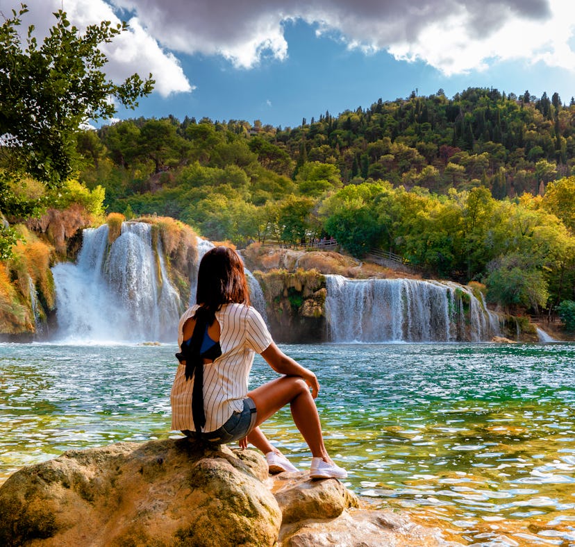 A woman admires waterfalls, for which she'll need a caption for the view and landscape captions.