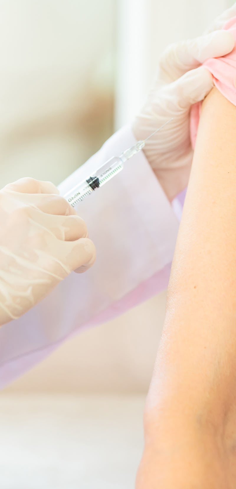 Closeup,asian female doctor with syringe doing injection vaccine,flu,influenza in the shoulder of se...