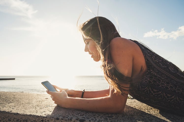 Beautiful long hair spanish woman use mobile phone to send message during a vacation in Tenerife. La...